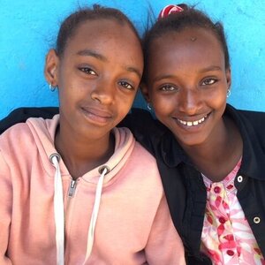 two girls sitting together and smiling